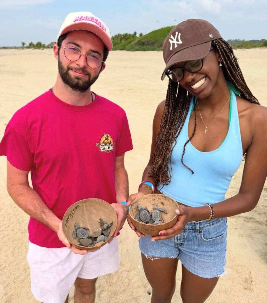 Pareja sosteniendo crías de tortuga durante experiencia de liberación en Escobilla.