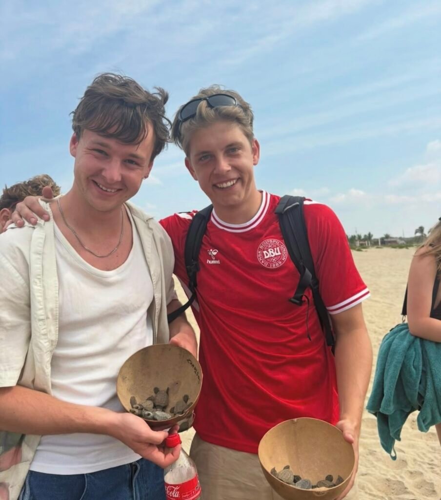 Pareja mostrando crías de tortuga durante experiencia en Escobilla, Oaxaca.